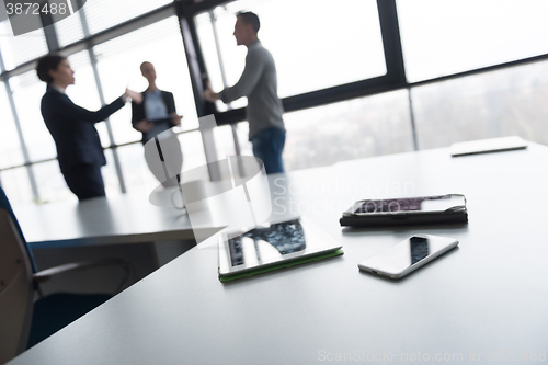 Image of close up of tablet, business people on meeting in background