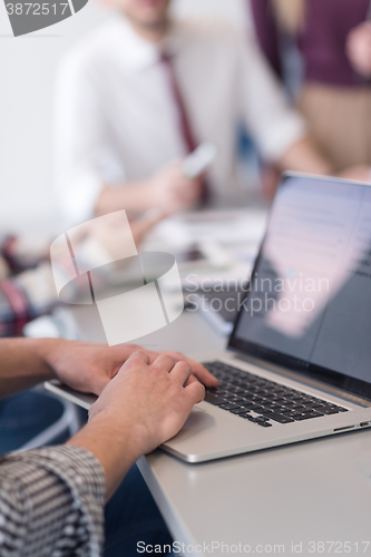 Image of close up of business man hands typing on laptop with team on mee
