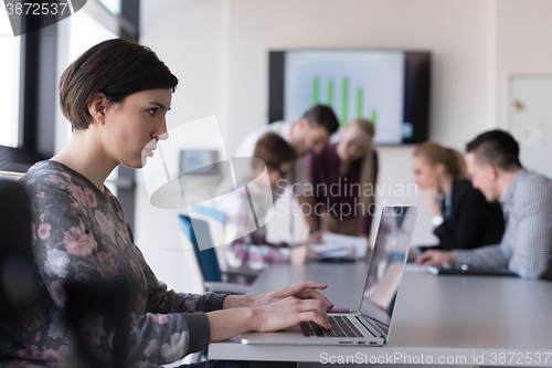 Image of young business woman at office working on laptop with team on me