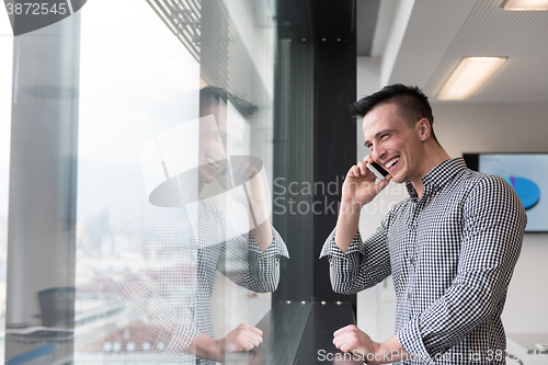 Image of young business man speaking on  smart phone at office