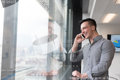 Image of young business man speaking on  smart phone at office