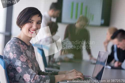 Image of young business woman at office working on laptop with team on me