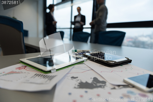 Image of close up of tablet, business people on meeting in background