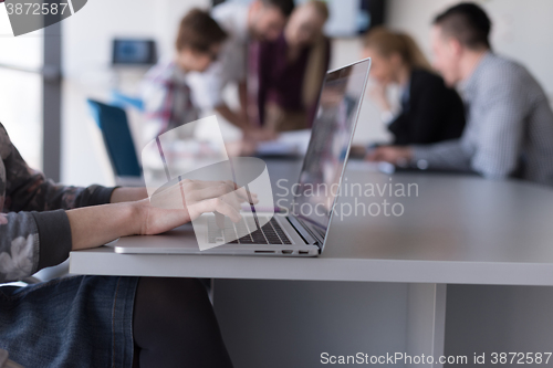 Image of close up of business womans hand typing on laptop with team on m