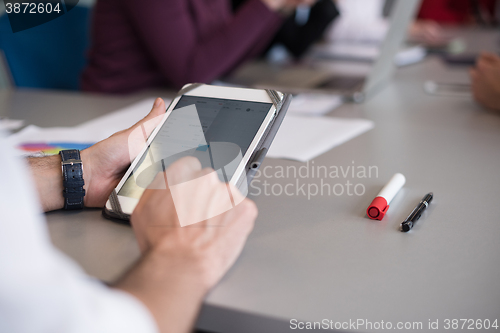 Image of close up of  businessman hands  using tablet on meeting