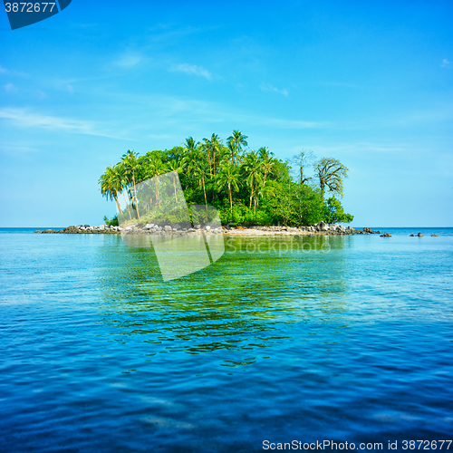 Image of  An atoll in the sea surrounded by blue sky and water with refle