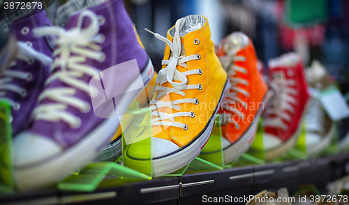 Image of Collection of colorful casual gumshoes on shelves in fashion sto