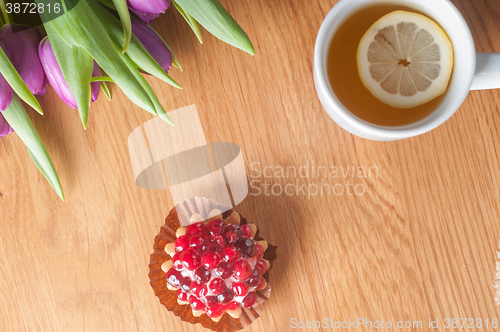 Image of Violet tulips, cake and tea on the wood