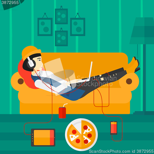 Image of Woman lying on sofa with many gadgets.