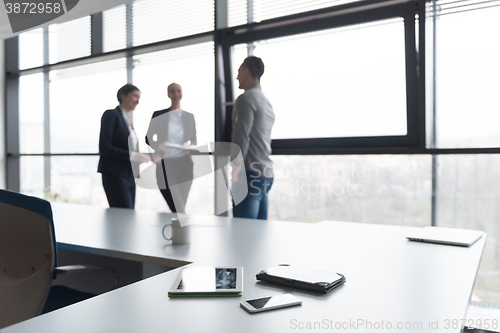 Image of close up of tablet, business people on meeting in background