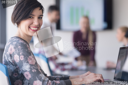 Image of young business woman at office working on laptop with team on me