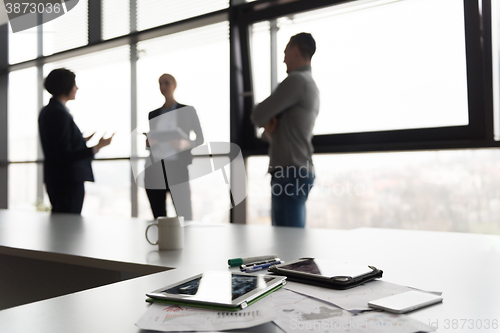 Image of close up of tablet, business people on meeting in background