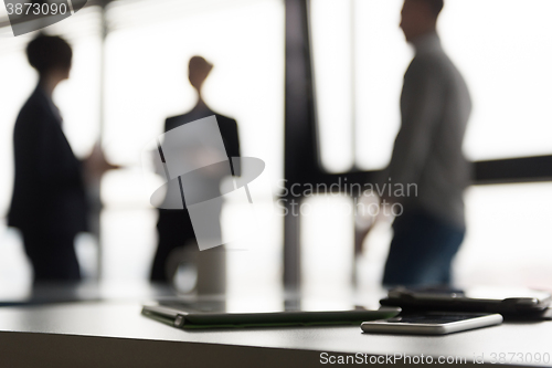 Image of close up of tablet, business people on meeting in background