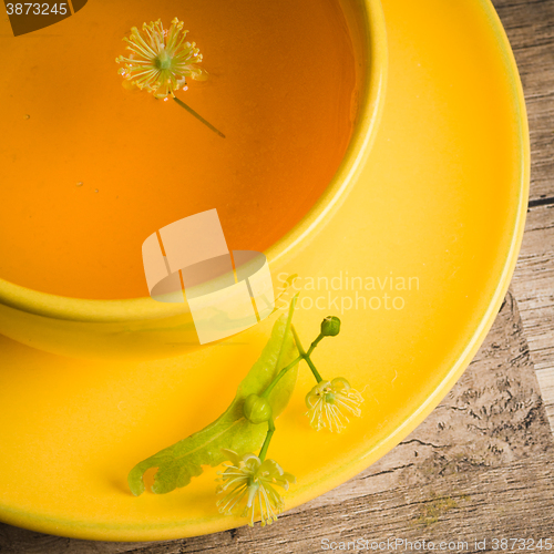 Image of Yellow cup with linden tea on the table,  top view