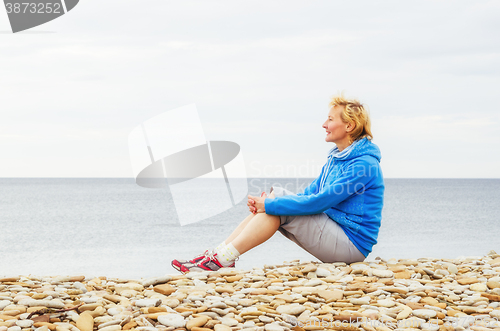 Image of Woman sitting on the beach and looks into the distance