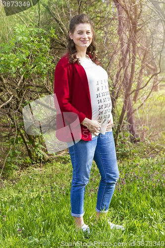 Image of Pregnant woman in red jacket with calendar on her T-shirt 