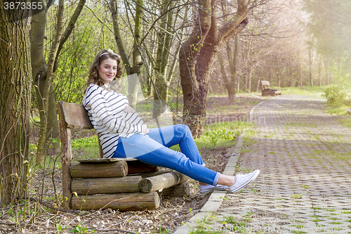 Image of beautiful pregnant woman outdoor in the park on banch