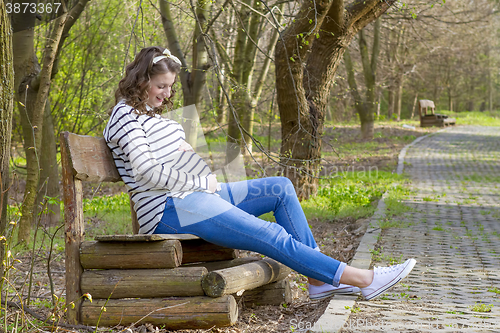 Image of beautiful pregnant woman outdoor in the park on banch