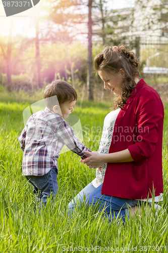 Image of beautiful pregnant woman outdoor with her little boy