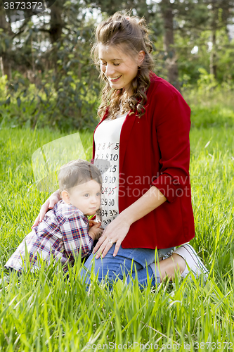 Image of beautiful pregnant woman outdoor with her little boy