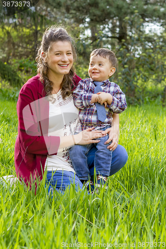 Image of beautiful pregnant woman outdoor with her little boy