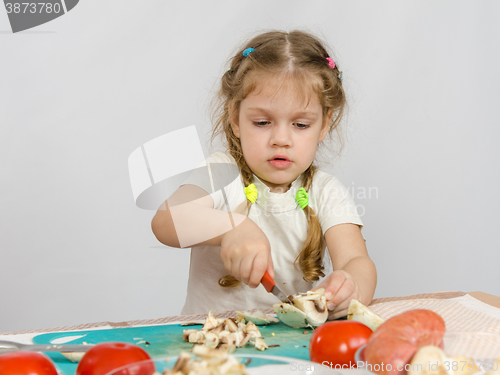Image of Five-year girl at the table hard cuts mushroom knife