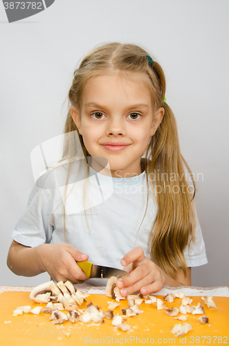 Image of Six year old girl at a table with a knife cutting mushrooms