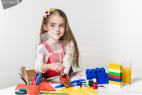 Image of Cute little girl drawing with paint and paintbrush at home