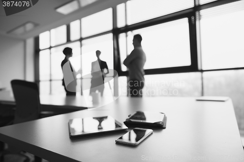 Image of close up of tablet, business people on meeting in background