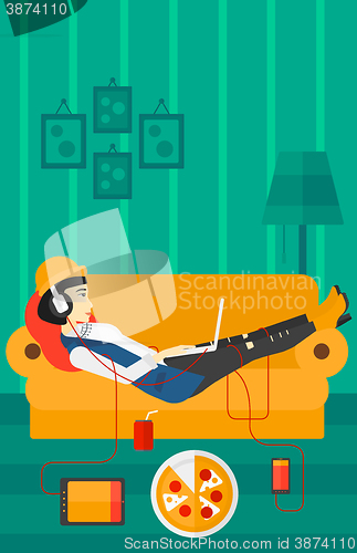 Image of Woman lying on sofa with many gadgets.