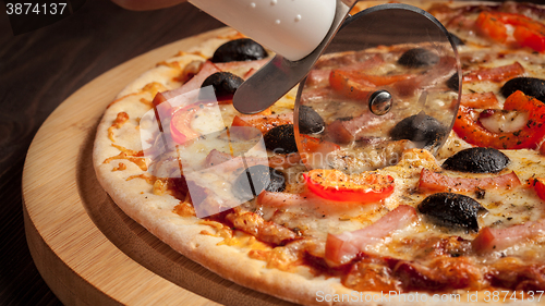 Image of Pizza cutter wheel slicing ham pizza 