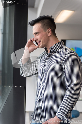 Image of young business man speaking on  smart phone at office