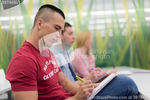 Image of male student taking notes in classroom