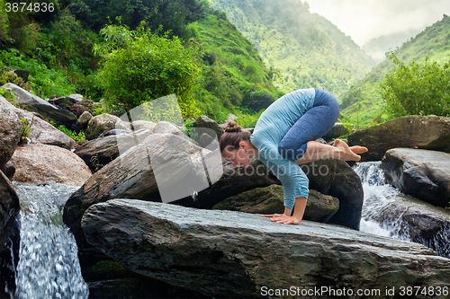 Image of Woman doing Bakasana asana outdoors