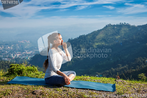 Image of Woman practices pranayama in lotus pose outdoors