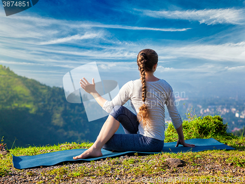 Image of Woman practices yoga asana Marichyasana 