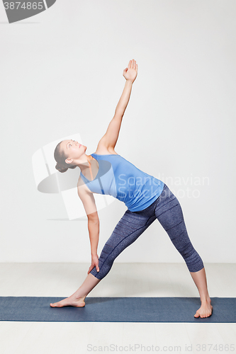 Image of Woman doing yoga asana utthita trikonasana