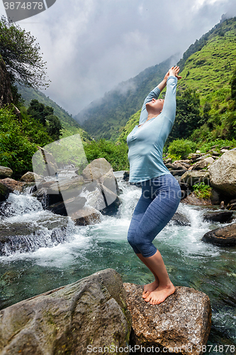 Image of Sorty fit woman doing yoga asana at waterfall