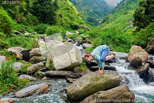 Image of Woman doing Kakasana asana arm balance outdoors