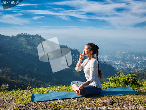 Image of Woman practices pranayama in lotus pose outdoors