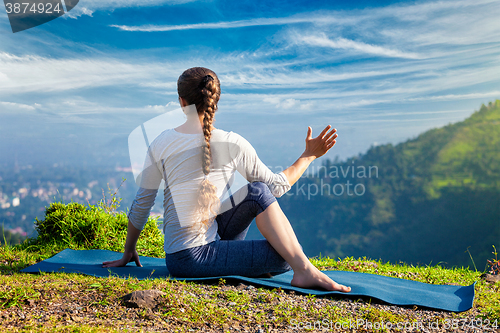 Image of Woman practices yoga asana Marichyasana 