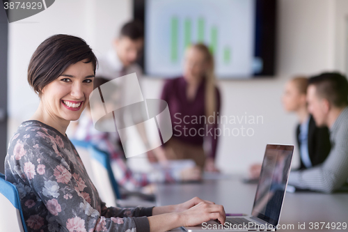 Image of young business woman at office working on laptop with team on me