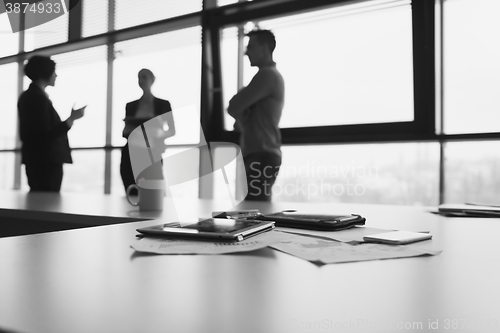 Image of close up of tablet, business people on meeting in background