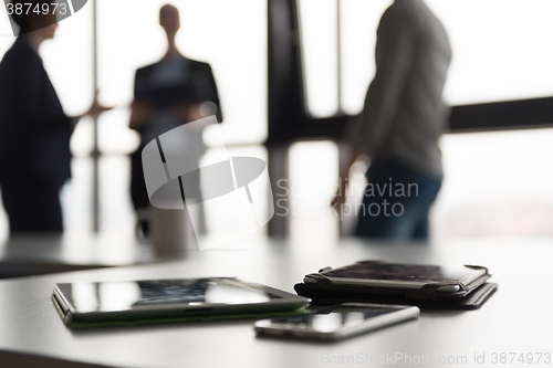 Image of close up of tablet, business people on meeting in background