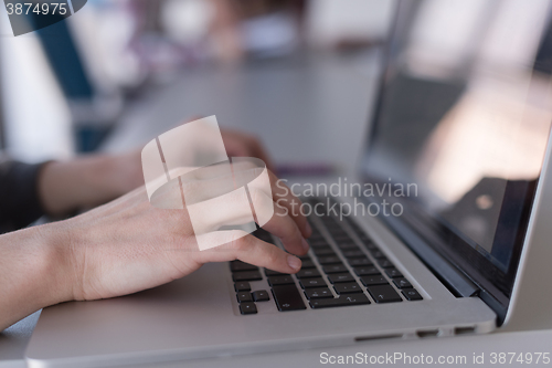 Image of close up of business womans hand typing on laptop with team on m