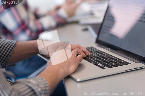 Image of close up of business man hands typing on laptop with team on mee