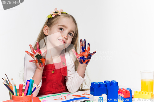 Image of The beautiful little girl with hands in the paint