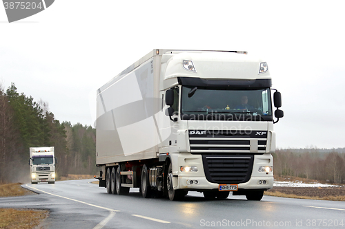 Image of Two White Semi Trucks on Rural Road