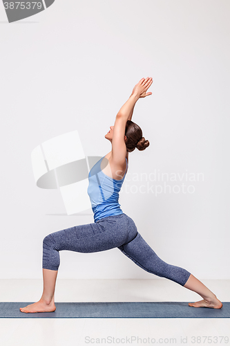 Image of Sporty woman practices yoga Warrior pose asana 