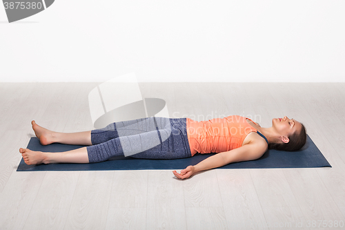 Image of Sporty fit girl relaxes in yoga asana Savasana